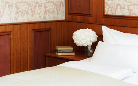 Hotelbett mit Blumen und Holzmöbeln