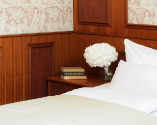 Hotelbett mit Blumen und Holzmöbeln