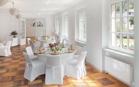 Geräumiger Veranstaltungsraum mit Holztischen und eleganten Stühlen.