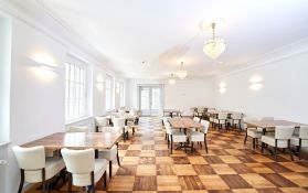 Geräumiger Veranstaltungsraum mit Holztischen und eleganten Stühlen.