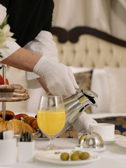 Zimmerservice mit Frühstück Ein Kellner serviert Frühstück im Hotelzimmer mit Croissants und Getränken.